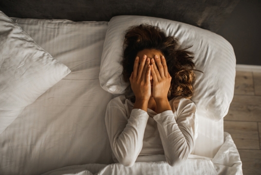 Frau liegt gestresst im Bett