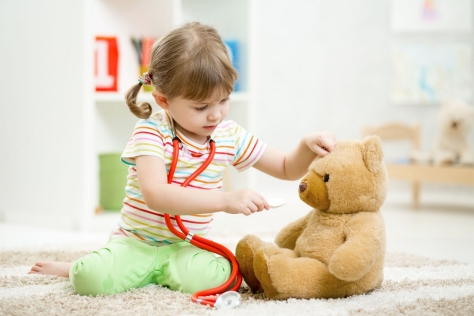 child girl playing doctor and curing plush toy