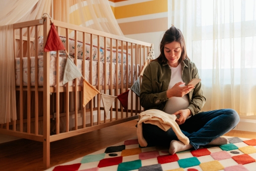 Frau sitzt schwanger in einem Kinderzimmer