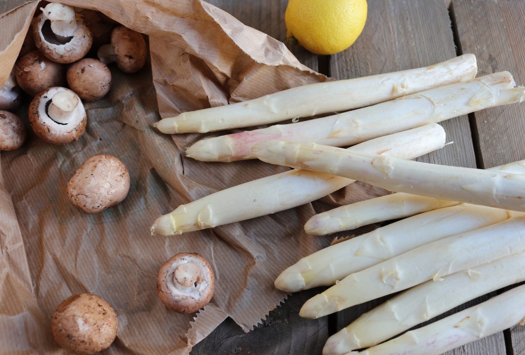 Spargel, Champignons und Zitrone auf einem Holztisch