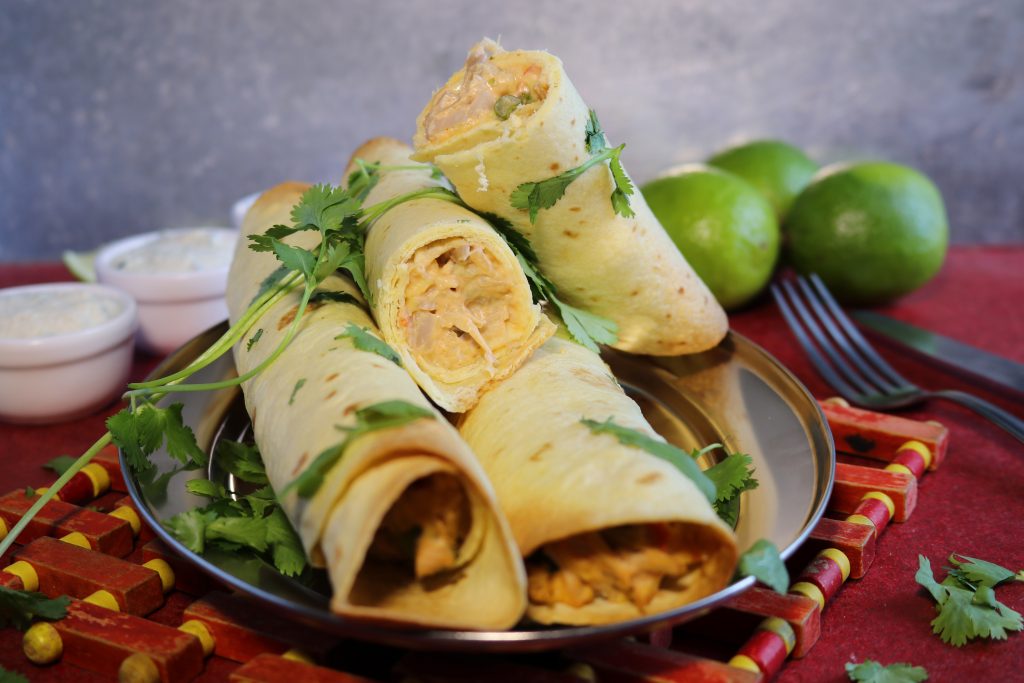 Vegane Chicken Taquitos mit Sour Cream Dip. Ein Taquitos ist angeschnitten, so dass man die Füllung gut sieht.