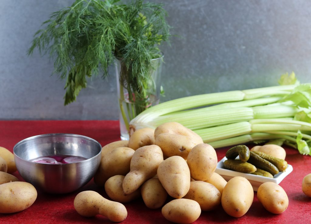 Kartoffeln, Gemüse und Dill auf einem roten Tisch