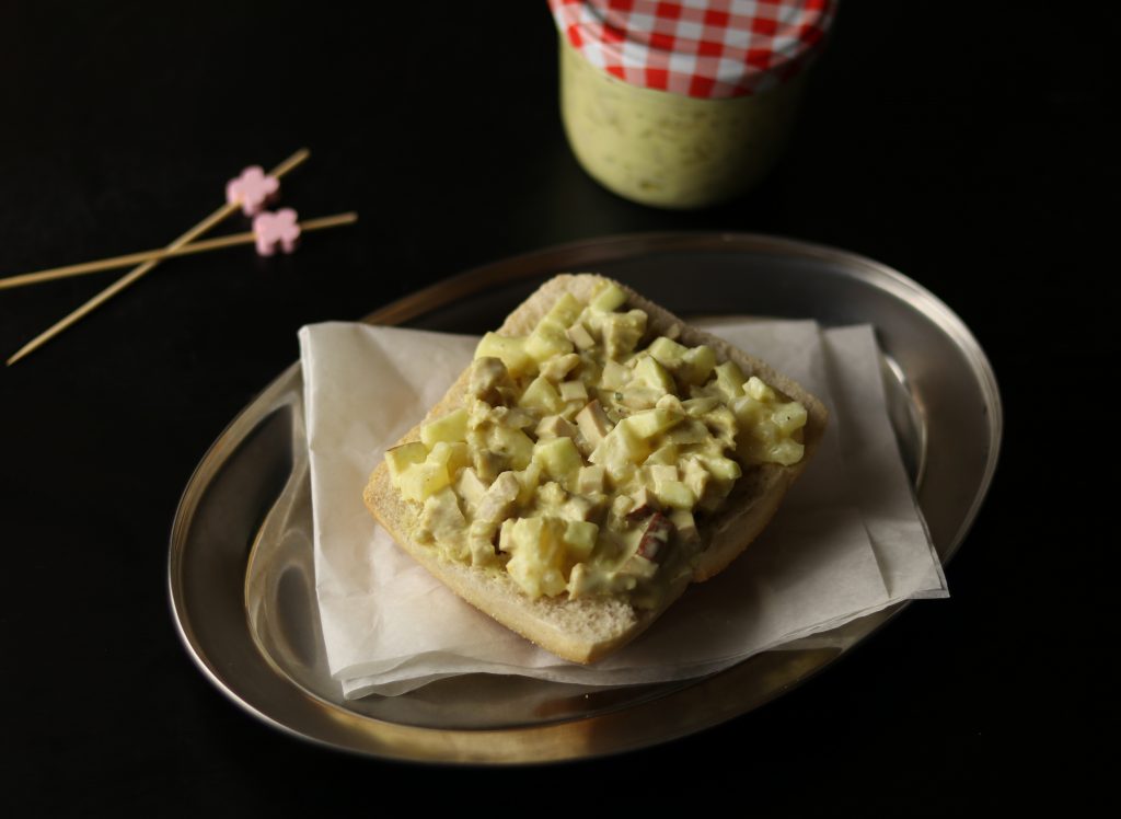 Curry-Geflügelsalat auf einem Brötchen und im Glas.