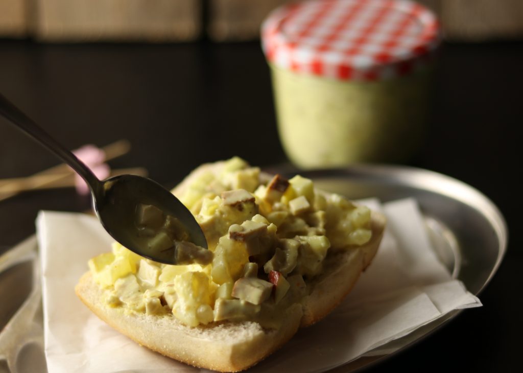 Curry-Geflügelsalat wird auf ein halbes Brötchen gegeben.