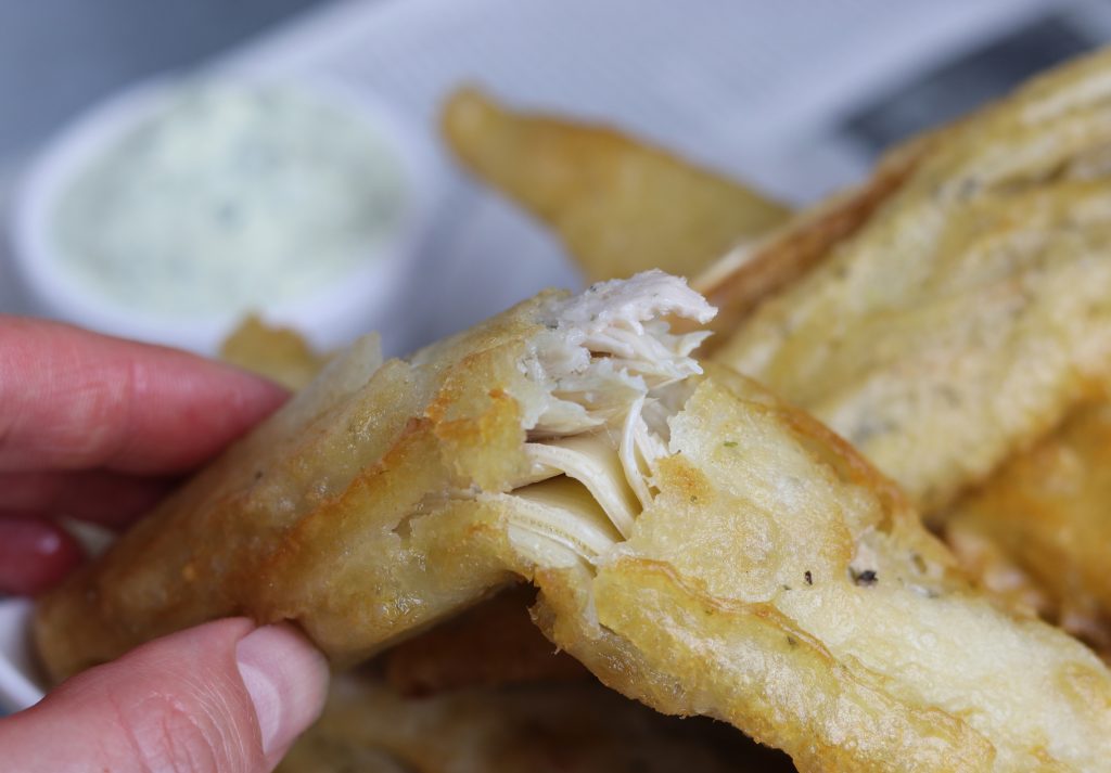Ein veganer Backfisch aus Bananenblüten wird angebrochen. Man sieht das zarte, strukturierte, authentische Fischfleisch.