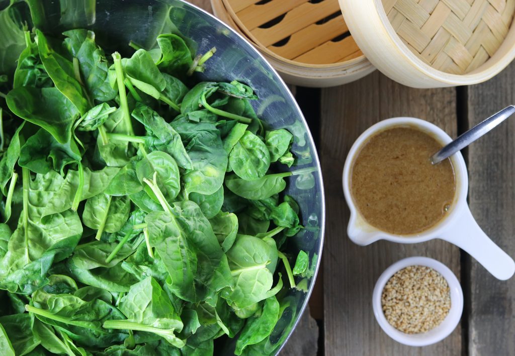 Ein Bambusdünsteinsatz sowie Zutaten für einen japanischen Spinat-Sesam-Salat.