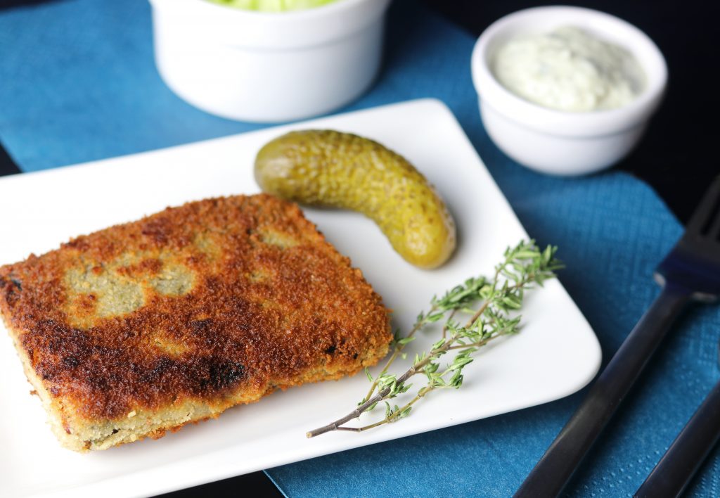 Leckerer Tofu-BackVisch. Einfach gemachter veganer Backfisch in knuspriger Panade! Mit saurer Gurke auf einem Teller.