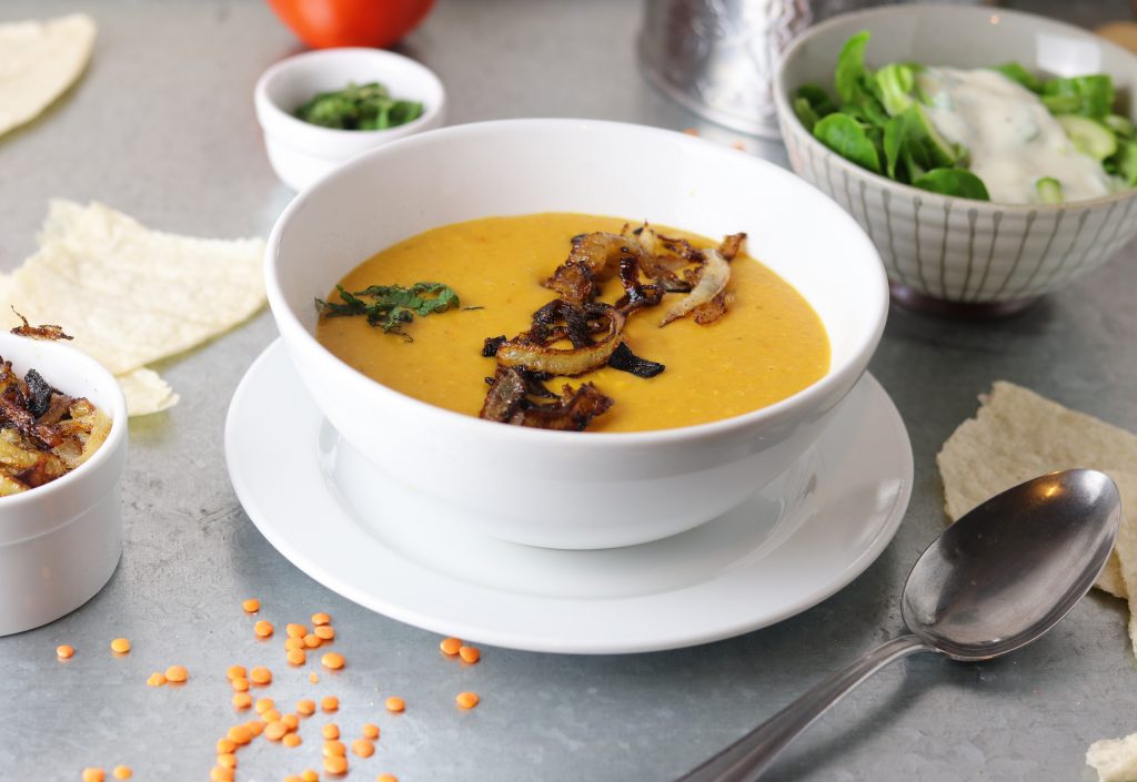 Dal, Dhal oder Daal in iner Schale mit gerösteten Zwiebeln, dazu Salt und Papadam.