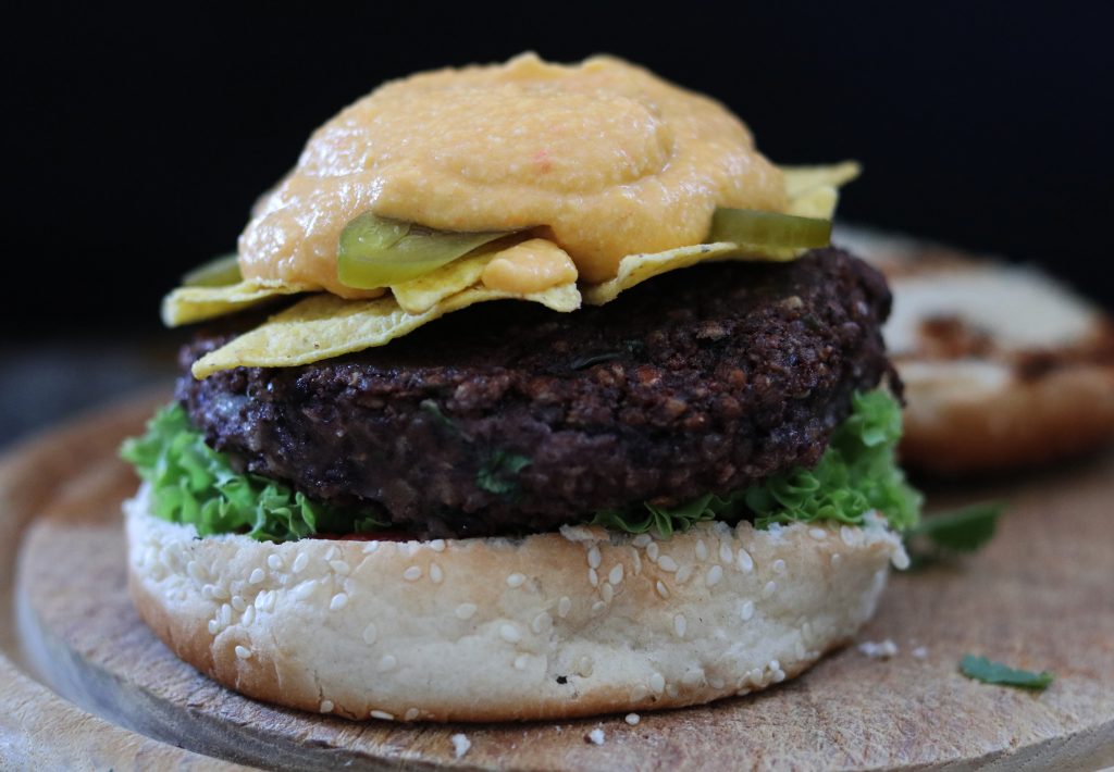 Belegen der Tex-Mex Nacho Burger: Tortilla Chips, Jalapenos und Keesesauce