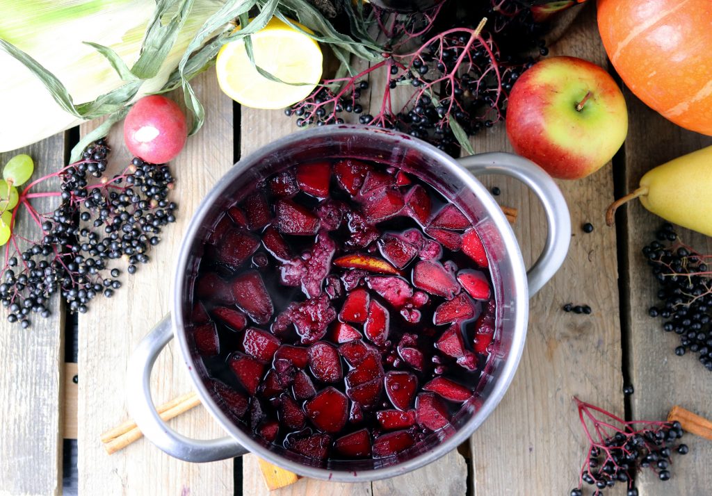 Frisch gekochte Fliederbeersuppe, daneben frische Fliederbeeren.