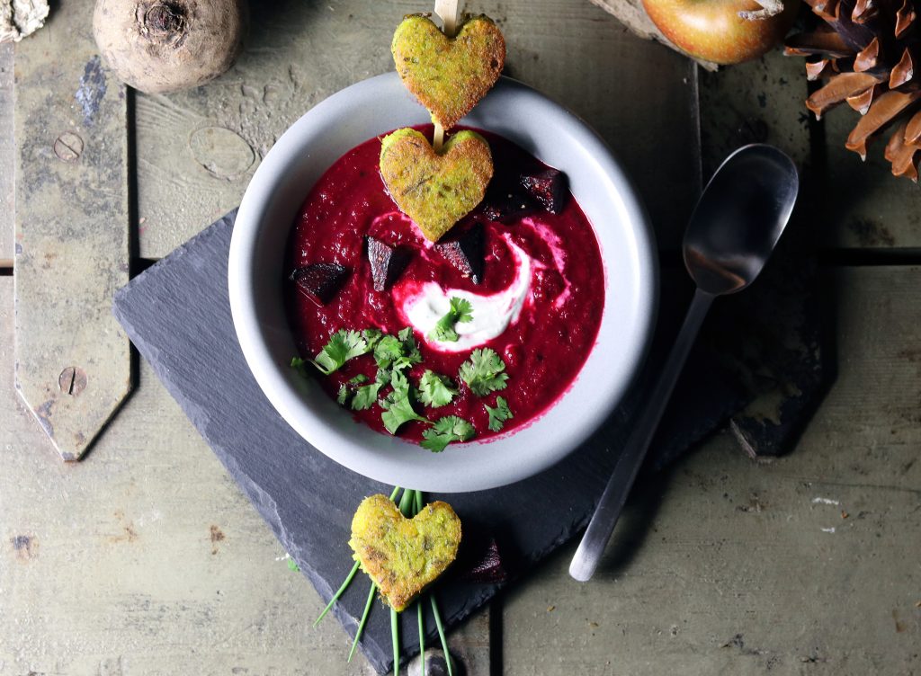 Rote Beete Apfel Suppe in einer Schüssel. Dazu grüne Polentaherzen mit selbstgemachter Bärlauchpaste