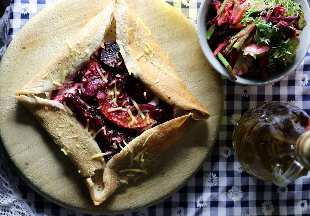 Galette belegt mit gebratenen Pflaumen, Rote Beete und Kürbis auf einer hellen Kräutercreme.