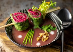 Würzige Beetehummus-Spinat-Spiralen auf einer lila Kartoffelsuppe