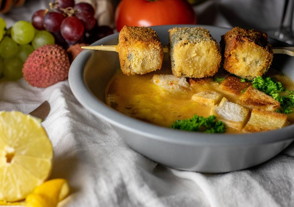 Vegane Sopa de Ajo mit gestocktem, veganem Ei in einer Schale. Darauf ein maritimer Spieß aus Tofu.