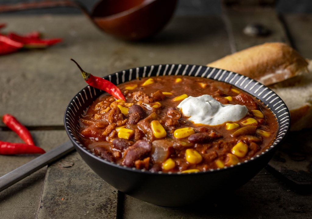 Eine Schüssel mit Chili sin Carne auf einer alten Holztruhe