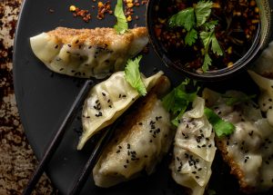Gyoza sind köstliche, kleine japanische Teigtaschen, die mit einer herzhaften Füllung aus Fleisch, Fisch oder Gemüse geformt werden.