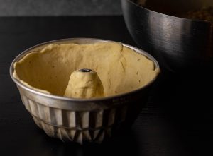 Eine Guglhupfform wurde mit Teig ausgekleidet und ist nun bereit zum Füllen.