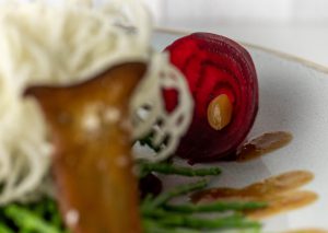 Haudünne Rote Beete Scheibe mit kleiner fermentierter Knoblauchzehe