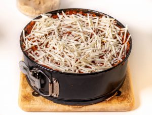 Mit reichlich Bolognese übergießen und mit veganem Käse bestreuen