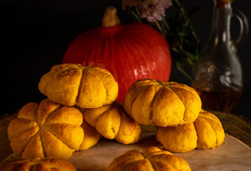 Kürbis Buns auf einem Holzbrett, dahinter ein Hokaidokürbis.