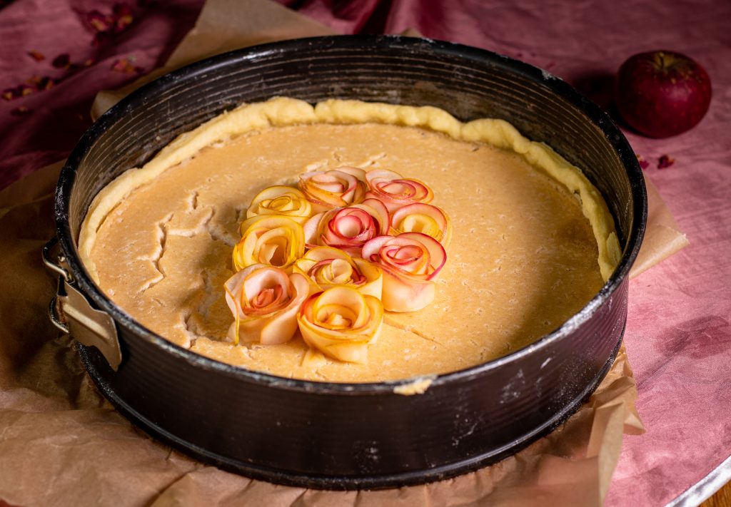 Belegen der Marzipan- und Puddingschicht mit den fertigen Apfelrosen