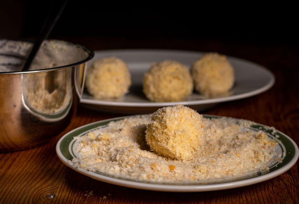 Vegane Mozzarellabällchen werden in Panko gewendet.