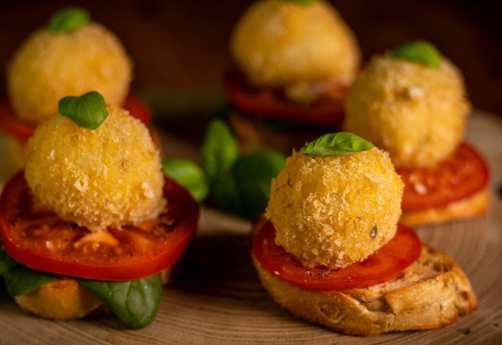 Frittierte Mozzarellabällchen - mit Tomatenscheiben und Basilikum auf geröstetem Brot