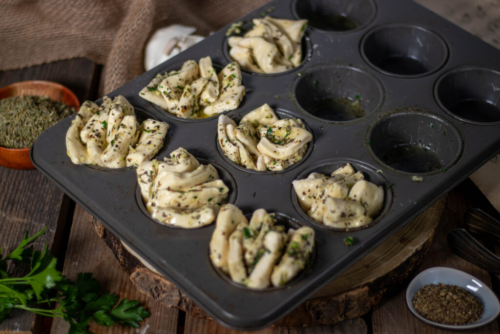 Der Hefeteig wurde ausgerollt und in Rechtecke geteilt. Diese werden dann mit der veganen Kräuterbutter eingepinselt, bevor sie in der Muffinform geschichtet werden, um dann noch Mal 20 MInuten zu gehen..
