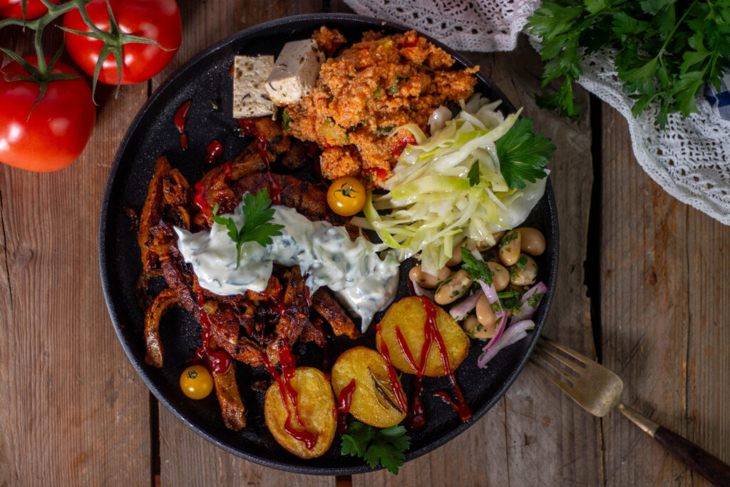 Ein reichhaltiger veganer Gyrosteller. MIt Gyros, Wedges, Piyaz, Krautsalat, Kisir, Veta und natürlich Tzatziki.