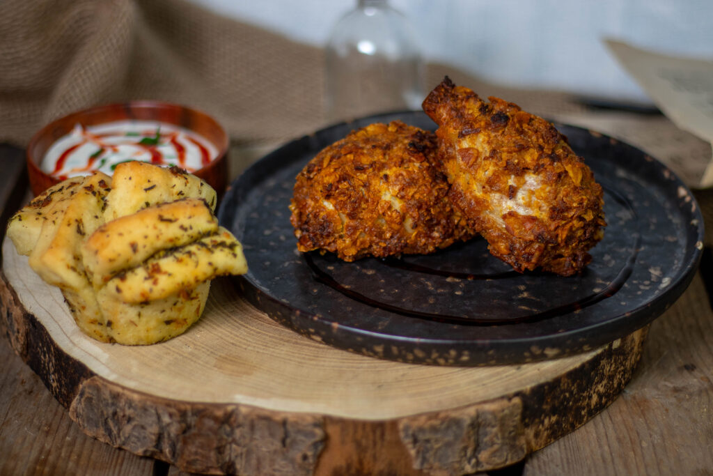 Vegane Hähnchenschenkel in Cornflakespanade mit Garlicky Pull-Apart Muffins und Dip als Beilagen.