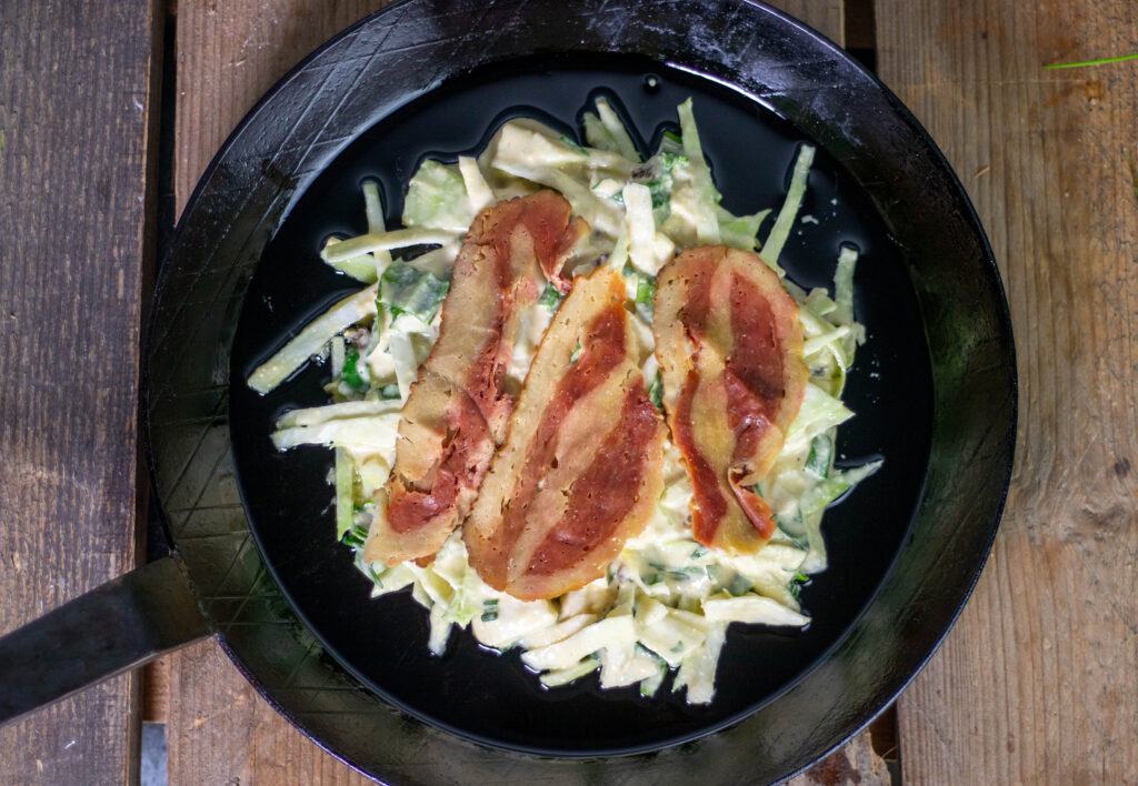 7. Die Hälfte des Okonomiteigs in die Pfanne geben und den veganen Schinken darauf legen.