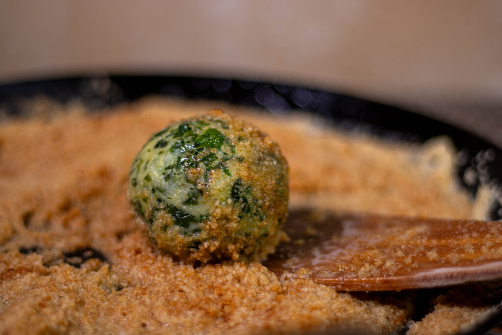 3. Wenden der Bärlauchknödel in der veganen Bröselbutter.