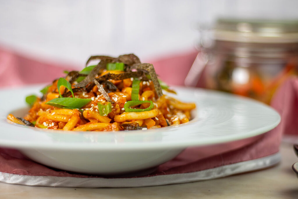 In diesem Rezept werden die würzigen Aromen von Kimchi mit den weichen, dicken Udon-Nudeln kombiniert