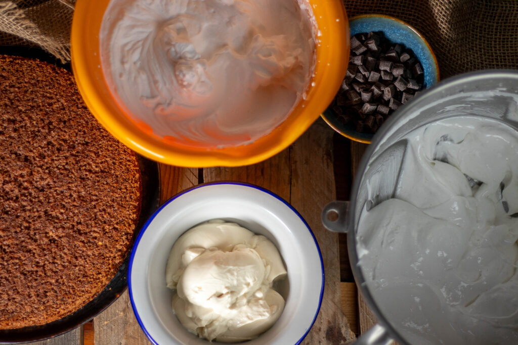 4. Die vegane Schaummasse, Schlagsahne, Quark, Schokostücke und Biskuit.