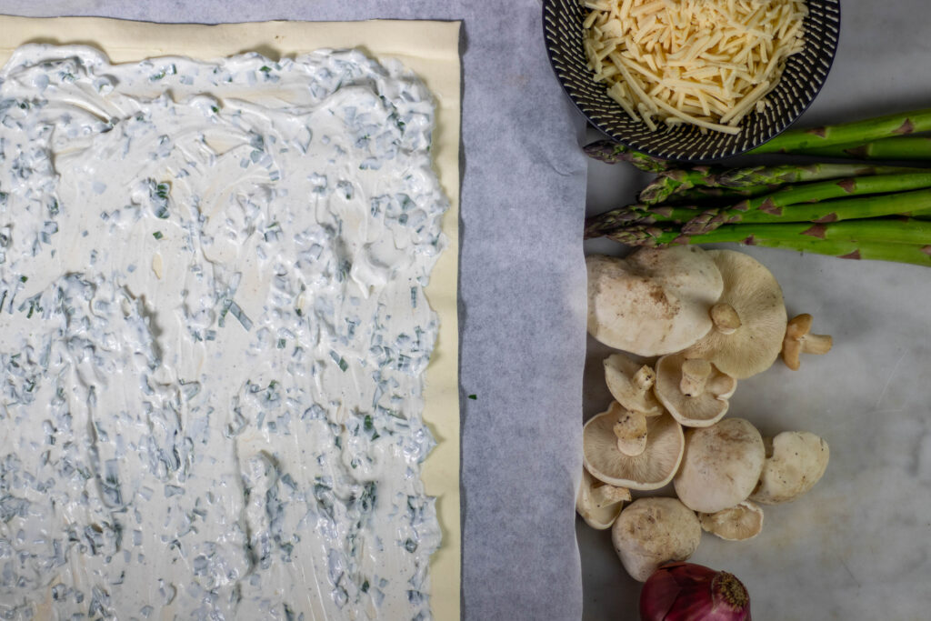 2. Mit Bärlauch gewürzte vegane Creme Fraiche wird auf dem Blätterteig verstrichen.