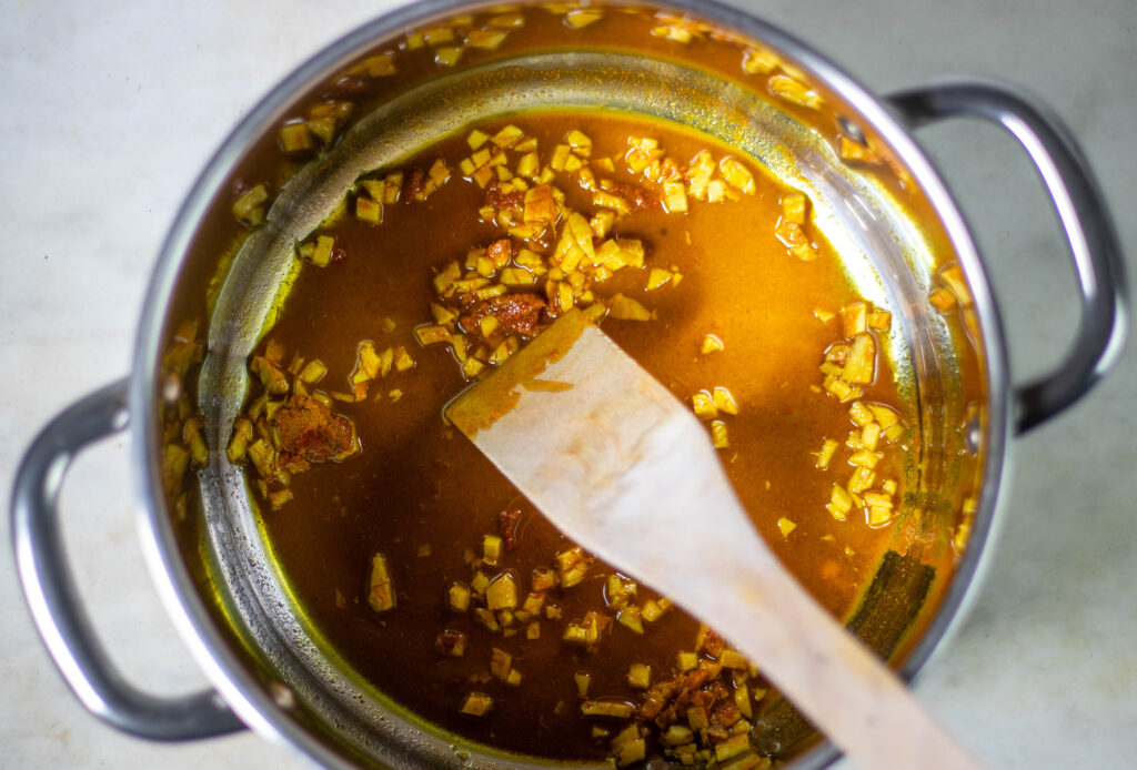 2. Etwas Öl in einem großen Topf erhitzen. Kurkuma, Kreuzkümmel, Koriander, Curry-Paste und Ingwer darin andünsten.