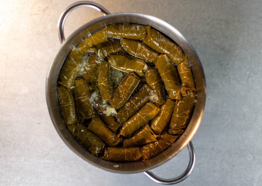 4. Olivenöl, Zitronensaft und Wasser über die Weinblätter geben, bis diese gerade eben bedeckt sind.