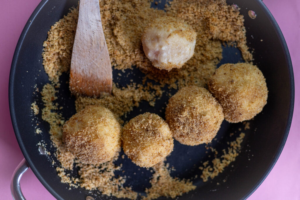 11. Die gegarten Marillenknödel werden in den süßen Zimtbröseln gewendet.