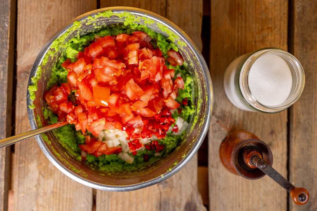 4. Nun können alle Zutaten miteinander verrührt und die Guacamole aus Erbsen mit Salz und Pfeffer abgeschmeckt werden.