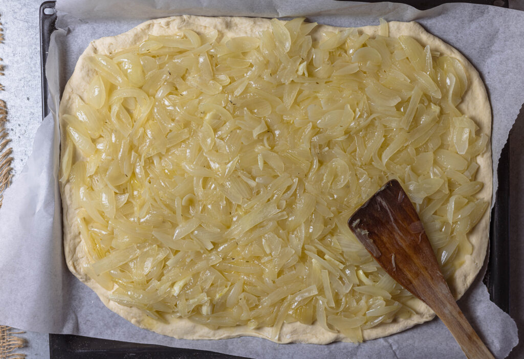 8. Der Teig wird gleichmäßig mit den Zwiebeln belegt.