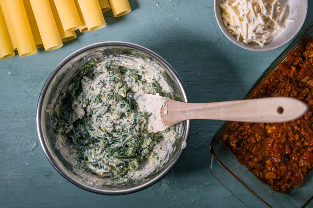 4. Spinat und Zwiebeln werden mit dem kalten, veganen Ricotta verrührt. Die Sahne wird mit dem Reibekäse vermengt.
