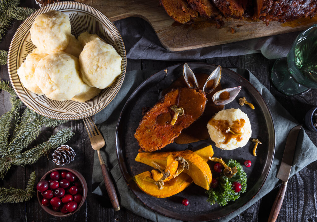 Vegane Kartoffelknödel mit veganem Sauerbraten, Kürbisspalten und eingelegten Pilzen
