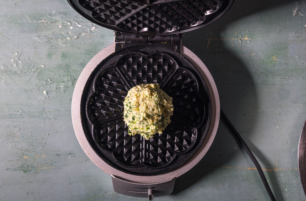 Roher Knödelwaffelteig in einem geöffneten Waffeleisen.