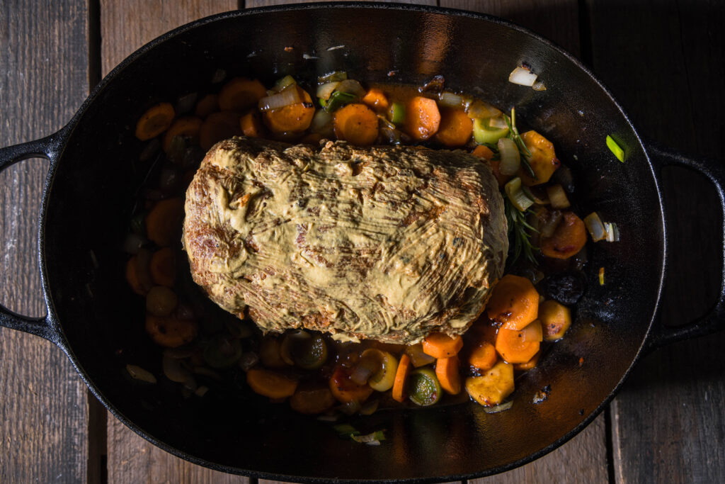 13. Den Braten mit Senf bestreichen und in den Bräter auf das Gemüse geben. Dann kommt der Schwarzbierbraten für 2 Stunden in den Ofen, dabei wird er mehrfach gewendet.
