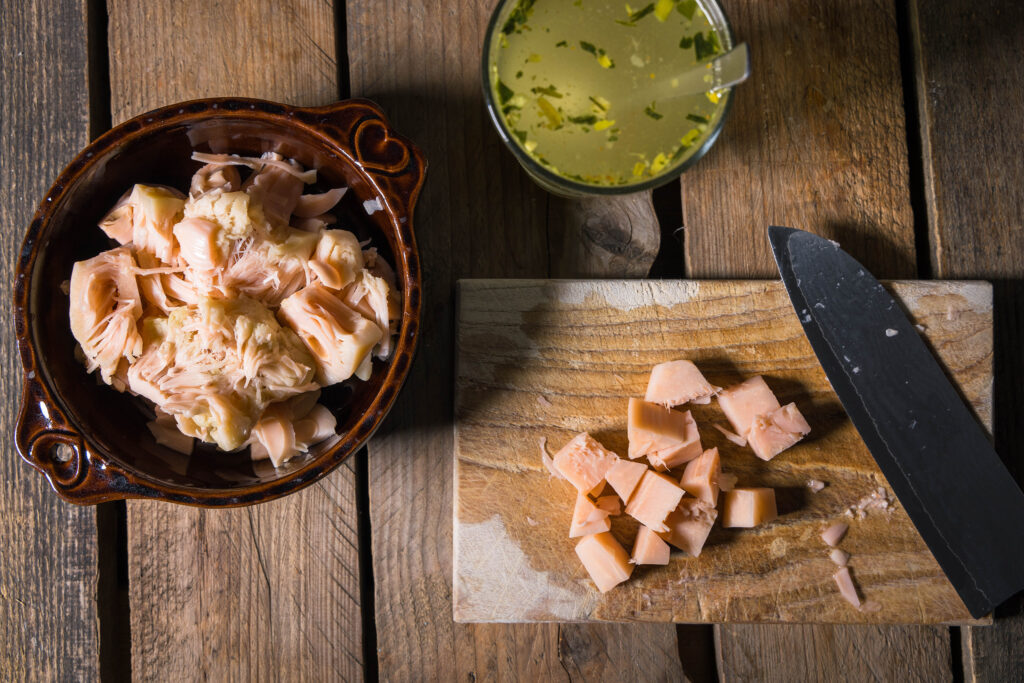2. Von den Jackfruitstücken die harten Spitzen entfernen, dann die Jackfruitfasern ausdrücken. Die Spitzen fein schneiden und wieder zur Jackfruit dazu geben.