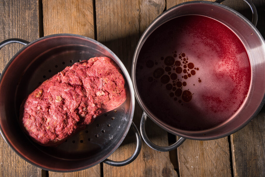7. Die Zutaten für den Sud mit der restlicehn Seitanflüssigkeit vermengen und zum Kochen bringen. Den rohen Schwarzbierbraten in einen Dünsteinsatz legen und 40 Minuten dünsten.