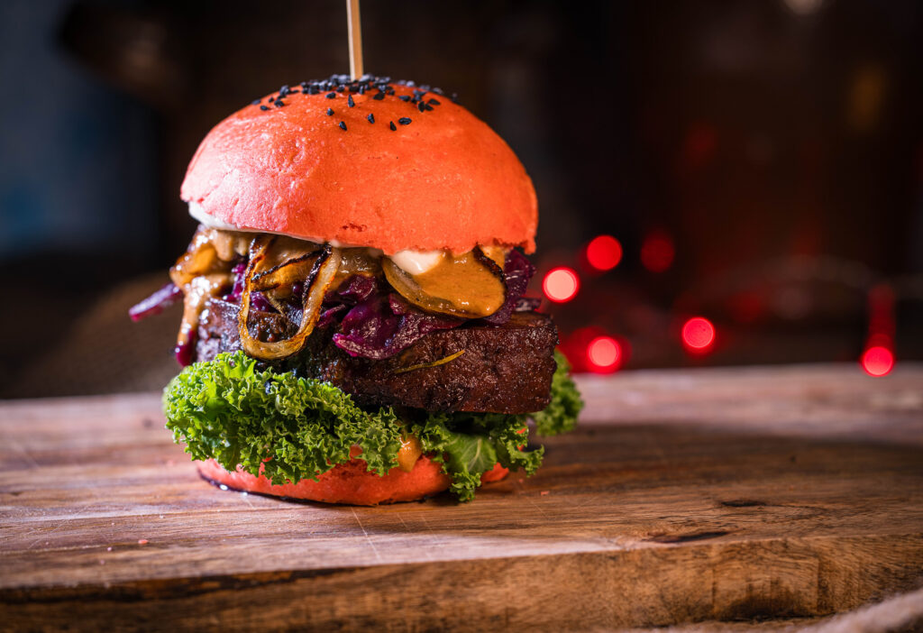 Weihnachtsburger auf Holzbrett, dahinter verschwommene rote Lichter