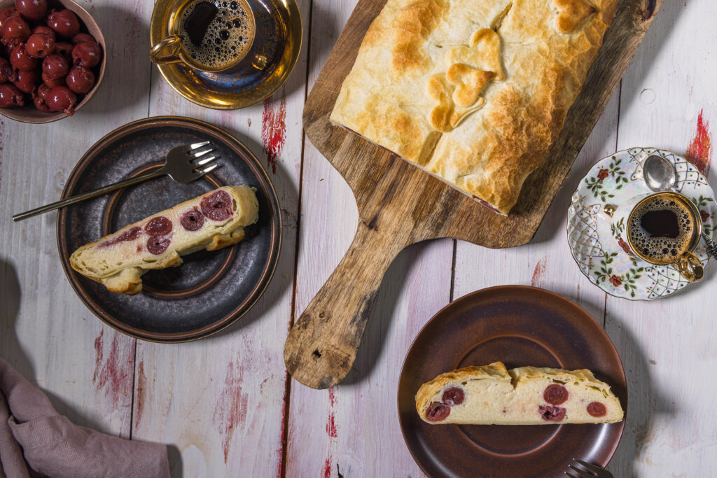 Veganer Qaurstrudel mit Kirschen von oben. Zwei Stücke mit Kuchengabeln auf Teller verteilt.