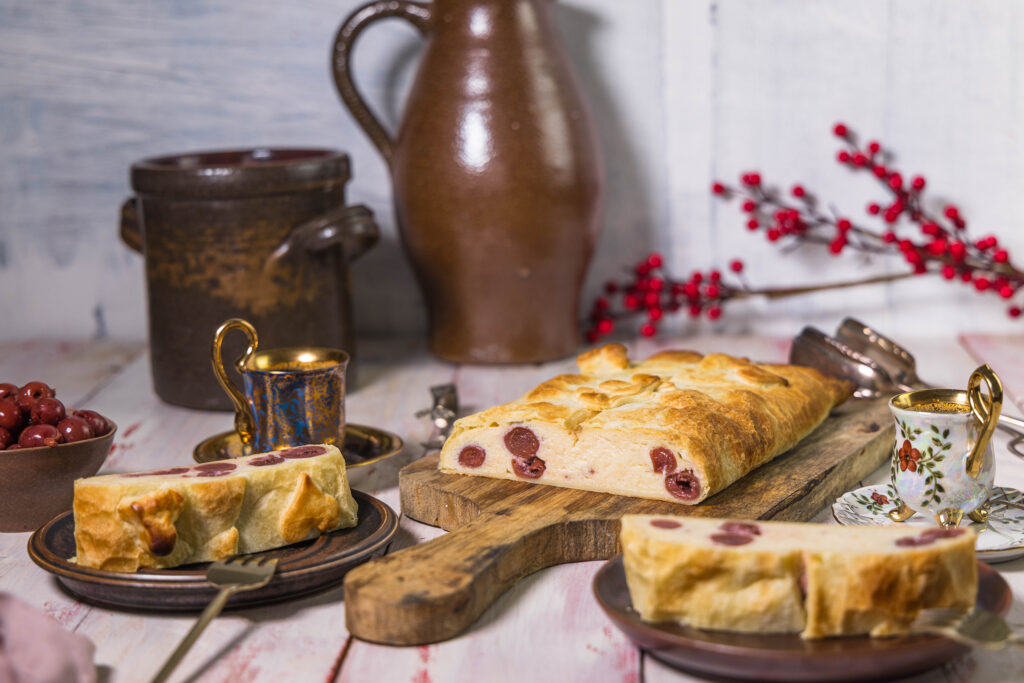 Veganer Quarkstrudel mit Kirschen und Blätterteig auf einer Kaffetafel.