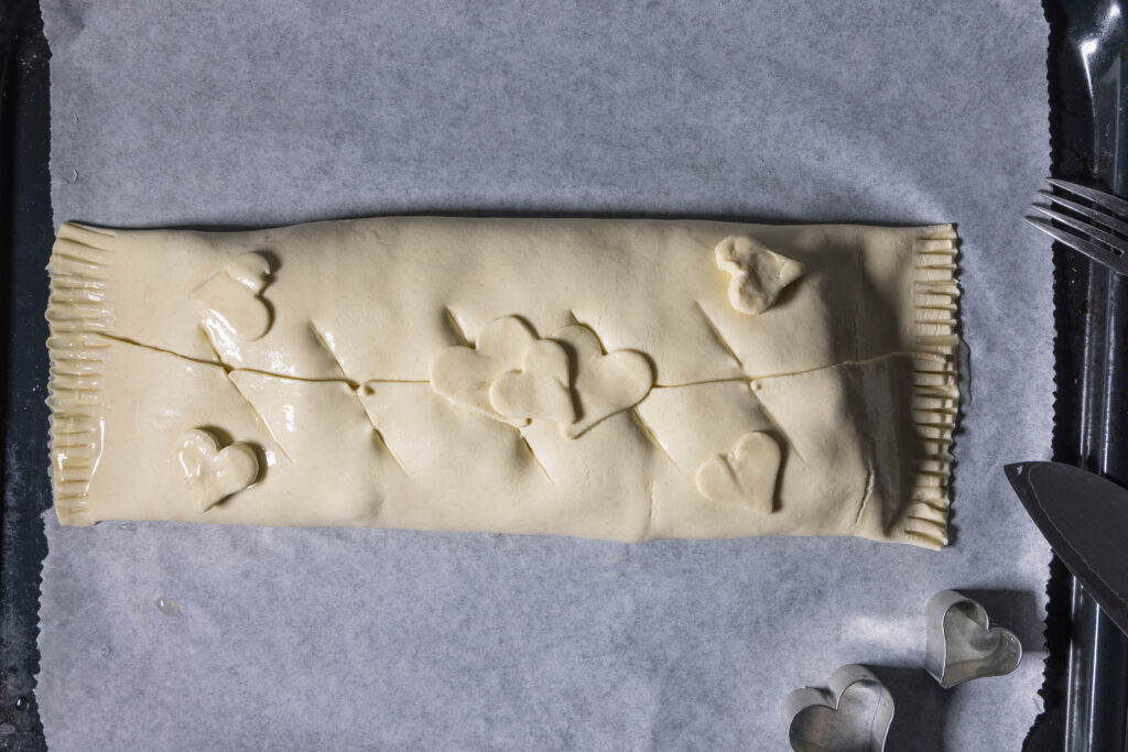 Ein roher Blätterteigstrudel, verziert mit Herzen aus Teig.